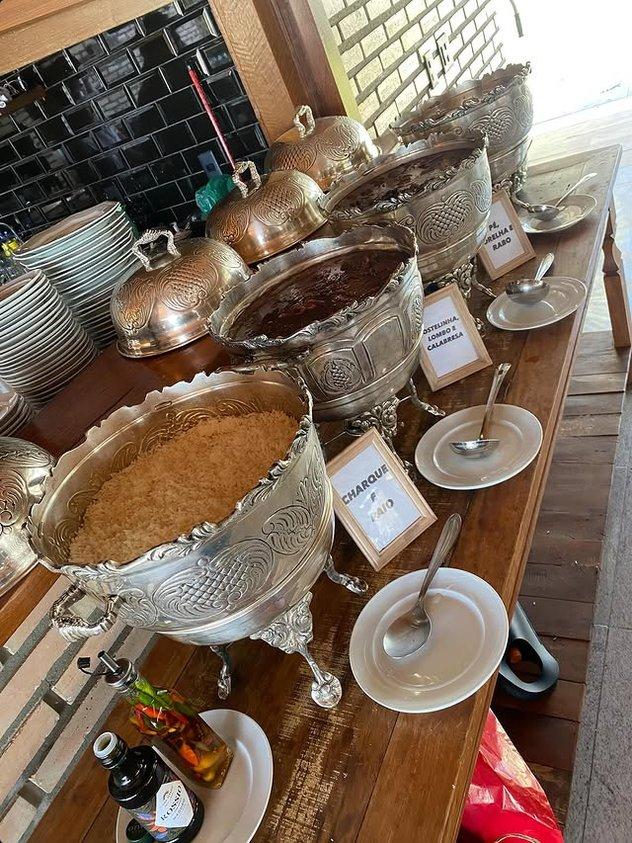 Buffet de feijoada completa servido em panelas de prata ornamentadas